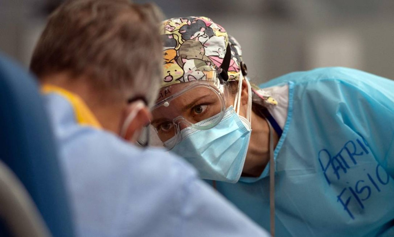 Fisioterapeuta examina um paciente com COVID-19 durante uma sessão no Hospital Isabel Zendal, em Madrid, Espanha Foto: PIERRE-PHILIPPE MARCOU / AFP