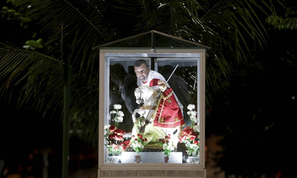 Leandro Ferreira, o Careca, que cuida há 11 anos da estátua de São Jorge na Rua Bernardo Guimarães, em Quintino, arruma o pequeno altar em homenagem ao santo Foto: Domingos Peixoto / Agência O Globo
