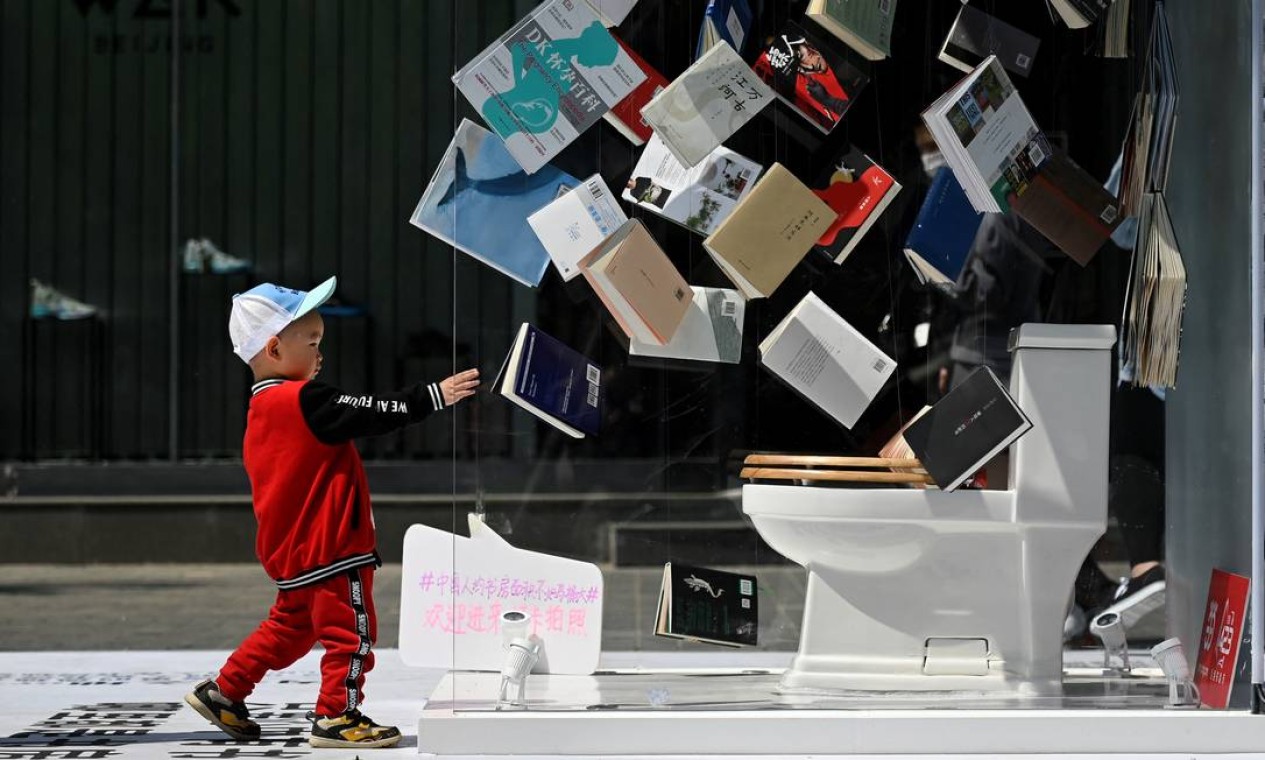 Criança interage com instalação de um estande promocional montado fora de um shopping no Dia Mundial do Livro, em Pequim Foto: WANG ZHAO / AFP
