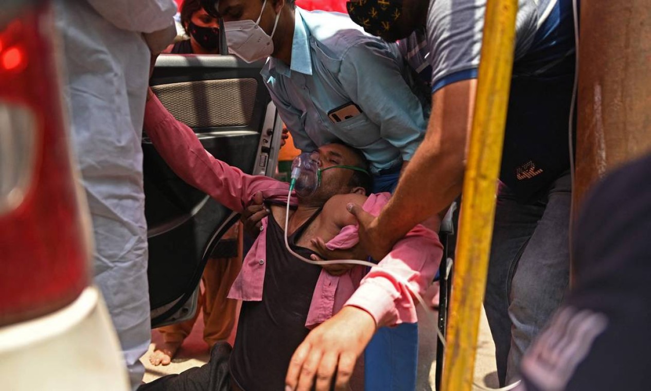 Paciente respira com a ajuda de oxigênio fornecido por um Gurdwara, um local de culto para os Sikhs, do lado de fora de um carro estacionado à beira da estrada em Ghaziabad, Índia Foto: SAJJAD HUSSAIN / AFP