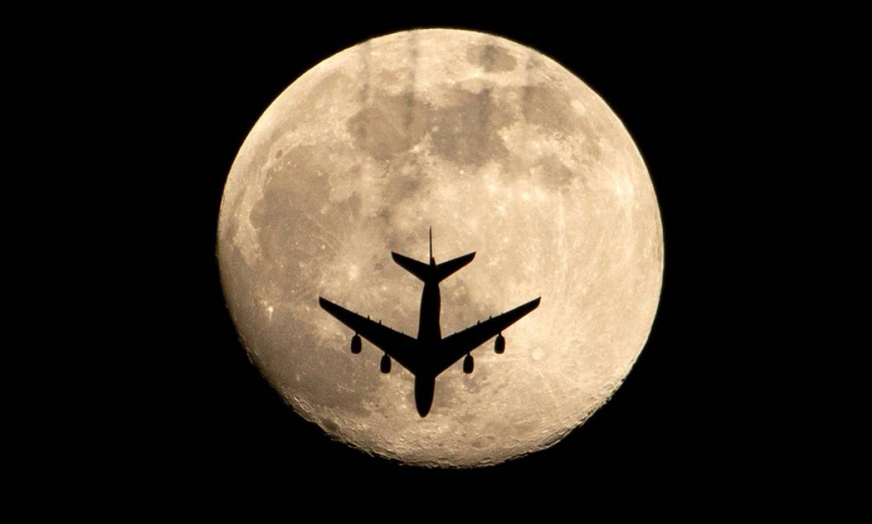 Avião é retratado contra a quase cheia "Lua Rosa", na cidade de Basra, no sul do Iraque Foto: HUSSEIN FALEH / AFP