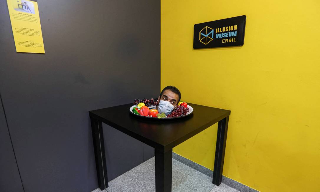 A visitor spies from a bowl of fruit, part of an optical illusion installation, at the Illusion Museum in Erbil, capital of the Kurdish Autonomous Region in northern Iraq (the table is a box with mirrors) Photo: Safin Hamed / AFP