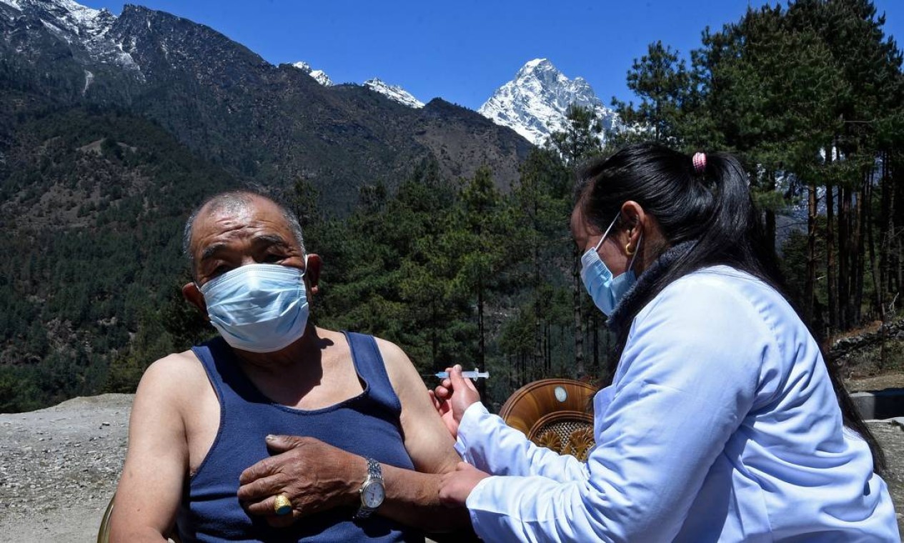 Um profissional de saúde inocula um homem com a dose da vacina Covishield contra o Covid-19 em um posto de saúde perto de Lukla, no nordeste do Nepal Foto: PRAKASH MATHEMA / AFP