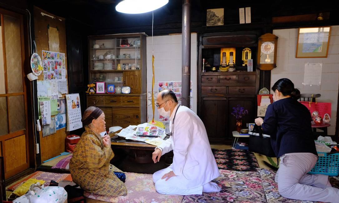 Profissionais de saúde conversam com Kakino Yamaguchi, depois de chegar a sua casa para inoculá-la com a vacina de coronavírus Pfizer-BioNTech Covid-19, na vila de Kitaaiki, onde vivem cerca de 350 famílias, na província de Nagano, no Japão Foto: KAZUHIRO NOGI / AFP
