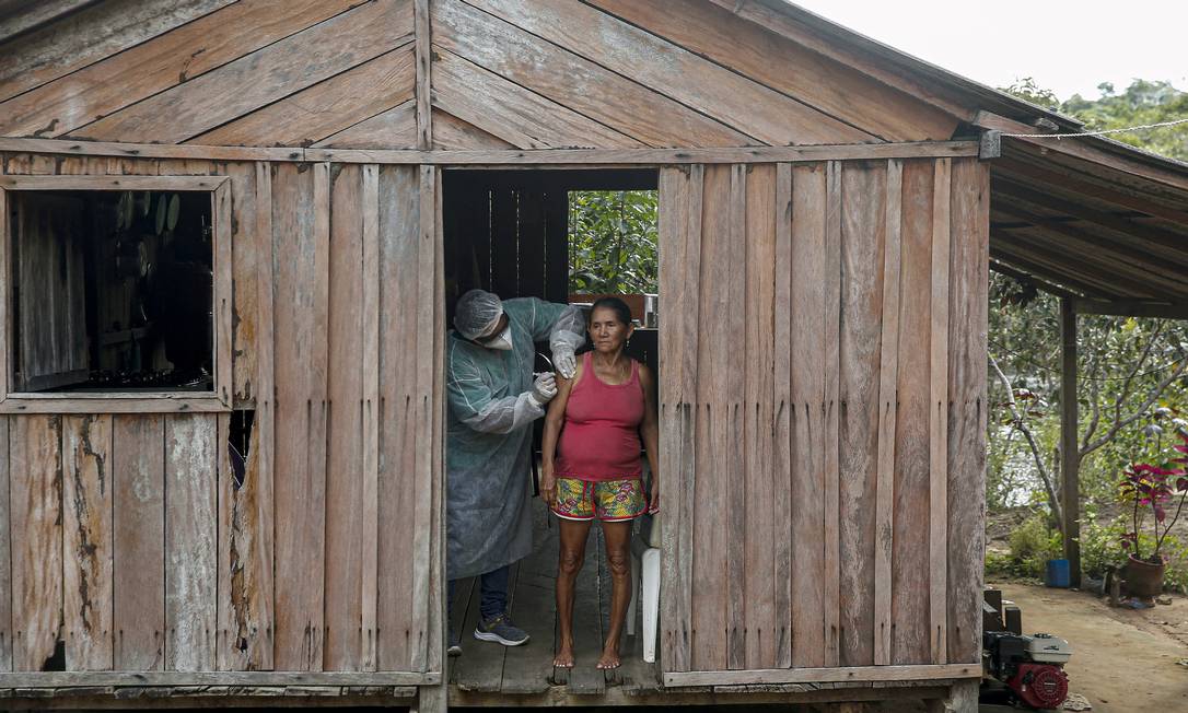 Trabalhador de saúde do Departamento de Saúde Indígena do Ministério da Saúde administra uma segunda dose de uma vacina COVID-19 à paciente Maria Tereza em São José III do rio Maro, na região do Baixo Amazonas no estado do Pará, próximo a Santarém Foto: TARSO SARRAF / AFP