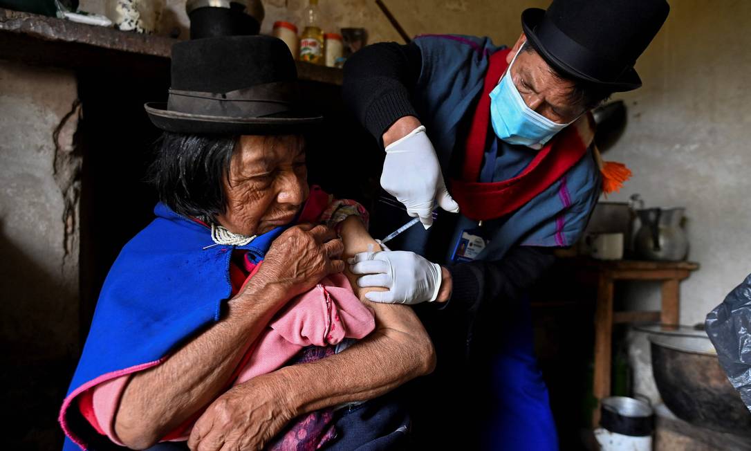 Enfermeira indígena da etnia Misak Anselmo Tunubala, 49, inocula uma idosa indígena com vacina Sinovac contra COVID-19 na reserva indígena Guambia, zona rural de Silvia, departamento de Cauca, Colômbia Foto: LUIS ROBAYO / AFP