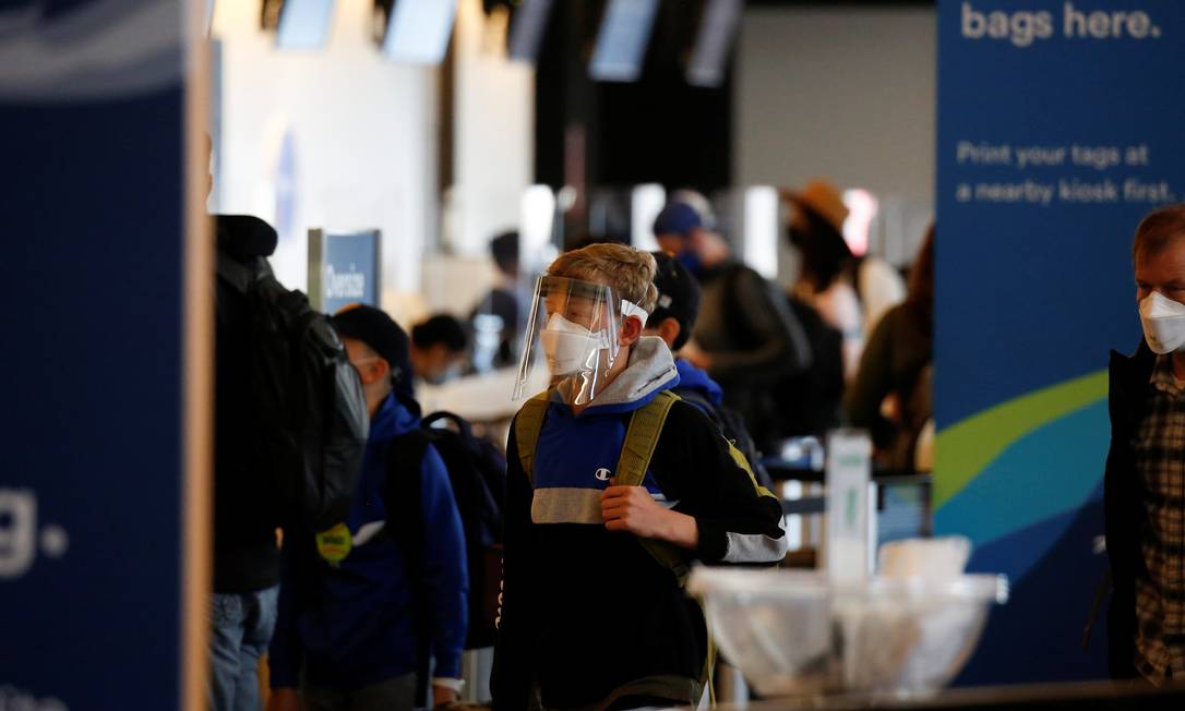 Jovem viaja com máscara e proteção facial no Aeroporto de Seattle Foto: LINDSEY WASSON / REUTERS