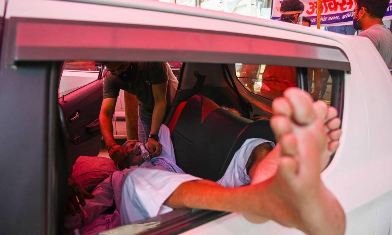 Paciente com Covid-19 deitado na traseira de um carro respira com a ajuda de oxigênio fornecido por um Gurdwara, um local de culto para Sikhs, ao longo de uma estrada em Ghaziabad Foto: PRAKASH SINGH / AFP
