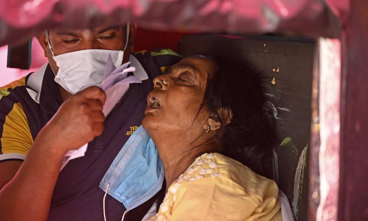 Paciente com Covid-19 deitado na traseira de um carro respira com a ajuda de oxigênio fornecido por um Gurdwara, um local de culto para Sikhs, ao longo de uma estrada em Ghaziabad Foto: SAJJAD HUSSAIN / AFP