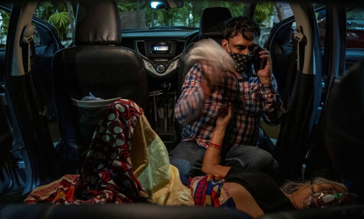 Manoj Kumar está sentado ao lado de sua mãe, Vidhya Devi, que estava sofrendo de um problema respiratório ao receber oxigênio gratuitamente dentro de seu carro em um Gurudwara (templo Sikh) Foto: DANISH SIDDIQUI / REUTERS