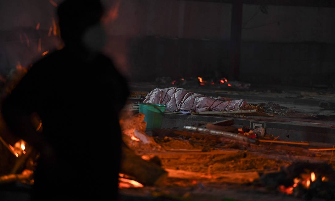 Cadáver de uma vítima do coronavírus Covid-19 antes da cremação ao lado de piras de outras vítimas no Crematório Nigambodh Ghat em Nova Delhi, Índia Foto: TAUSEEF MUSTAFA / AFP