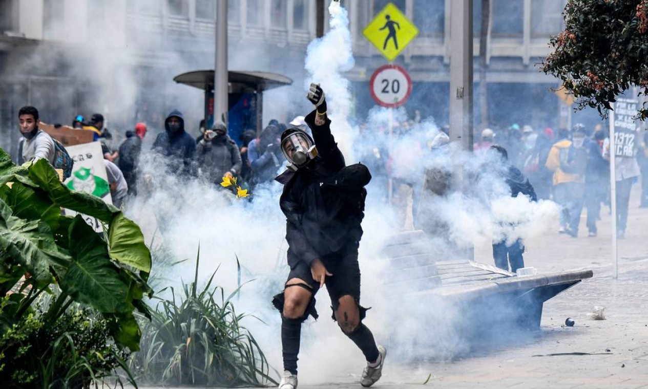 TOPSHOT - Um manifestante joga uma bomba de gás lacrimogêneo contra a tropa de choque durante um protesto contra um projeto de reforma tributária lançado pelo presidente colombiano Ivan Duque, em Bogotá Foto: Juan Barreto / AFP