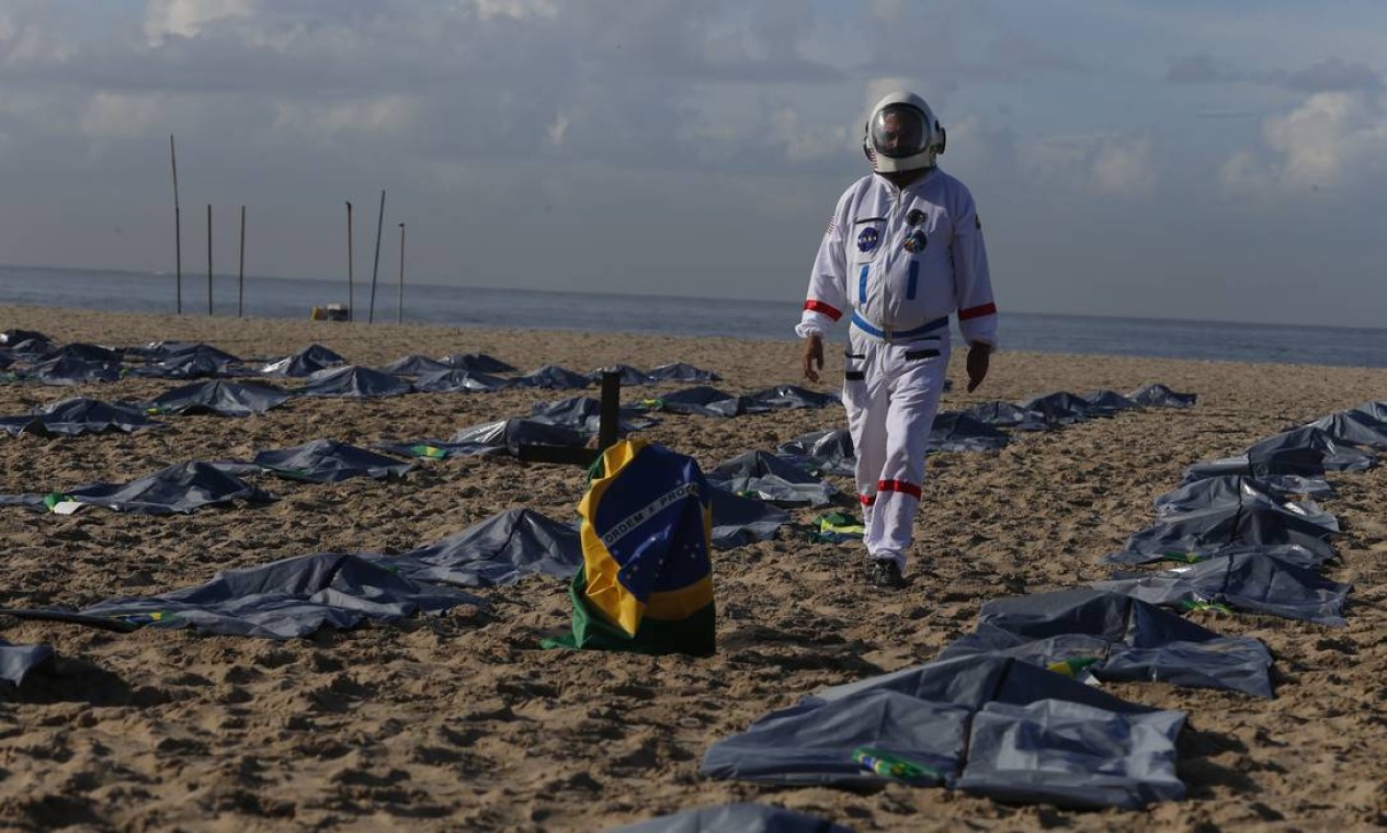 Manifestante caminha entre sacos usados na remoção de corpos para simbolizar as vítimas da pandemia Foto: Fabiano Rocha / Agência O Globo