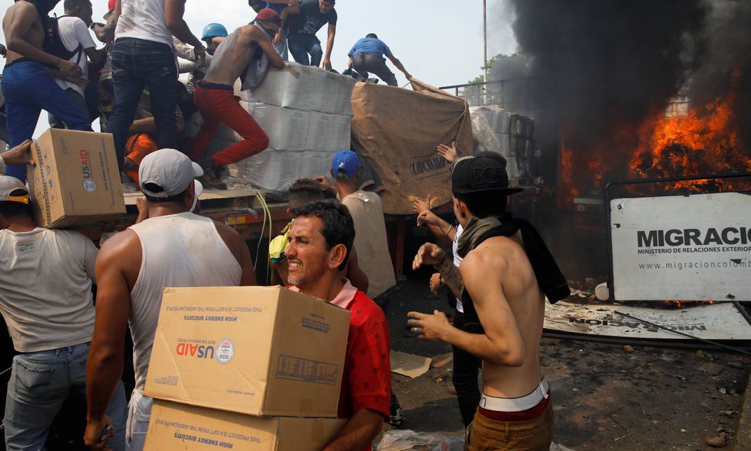 Opositores venezuelanos descarregam um caminhão de ajuda humanitária que foi incendiado após confronto entre os opositores e as forças de segurança da Venezuela na fronteira entre Colômbia e Venezuela, em 2019 Foto: Marco Bello / Reuters