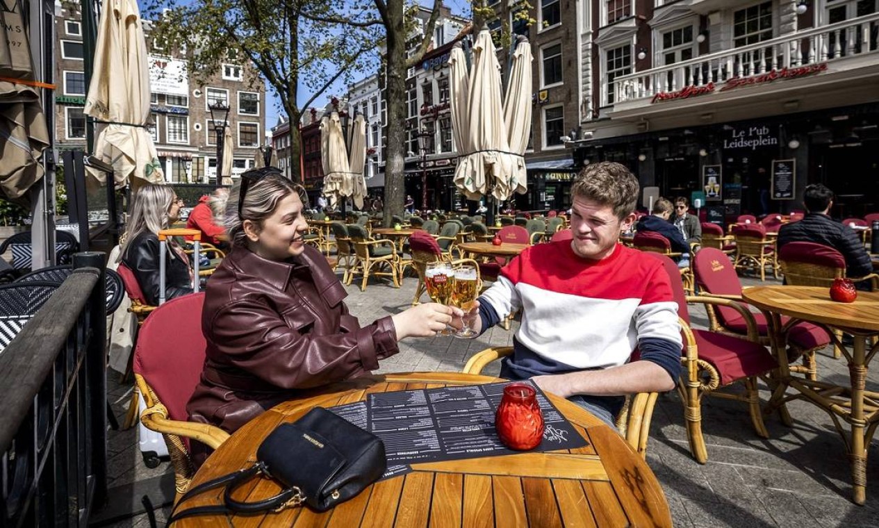 Na Holanda, a decisão do governo nacional de reabrir bares e cafés para serviços ao ar livre, desde o dia 28 de abril, foi celebrada com brindes nas ruas de Amsterdã Foto: REMKO DE WAAL / AFP