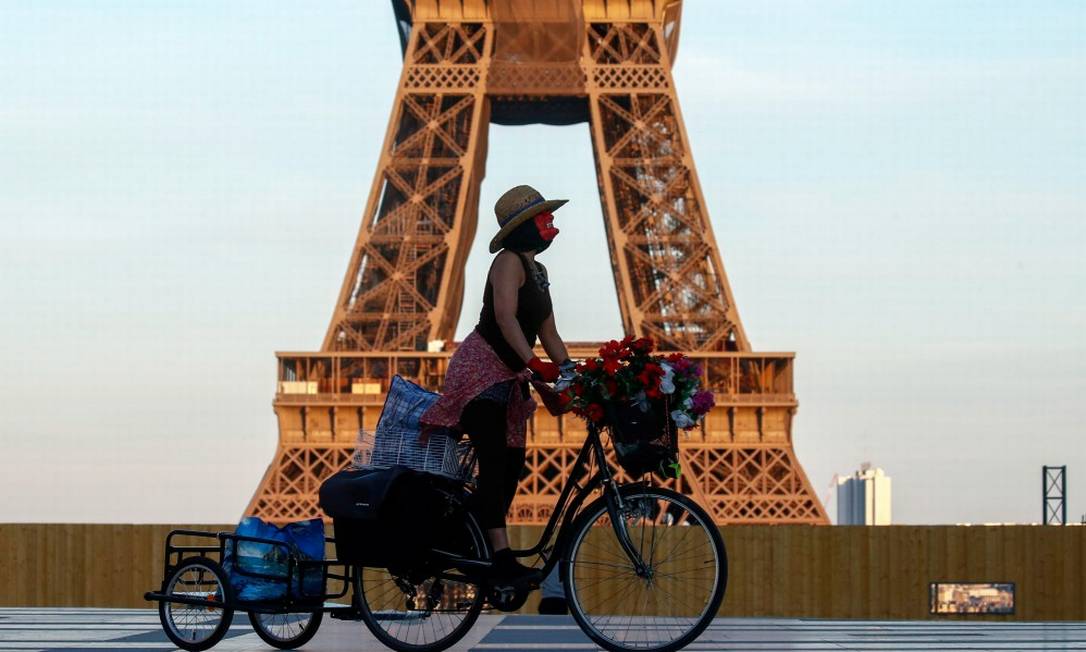 De máscara, mulher pedala em frente à Torre Eiffel, em Paris Foto: GONZALO FUENTES / REUTERS/26-4-21
