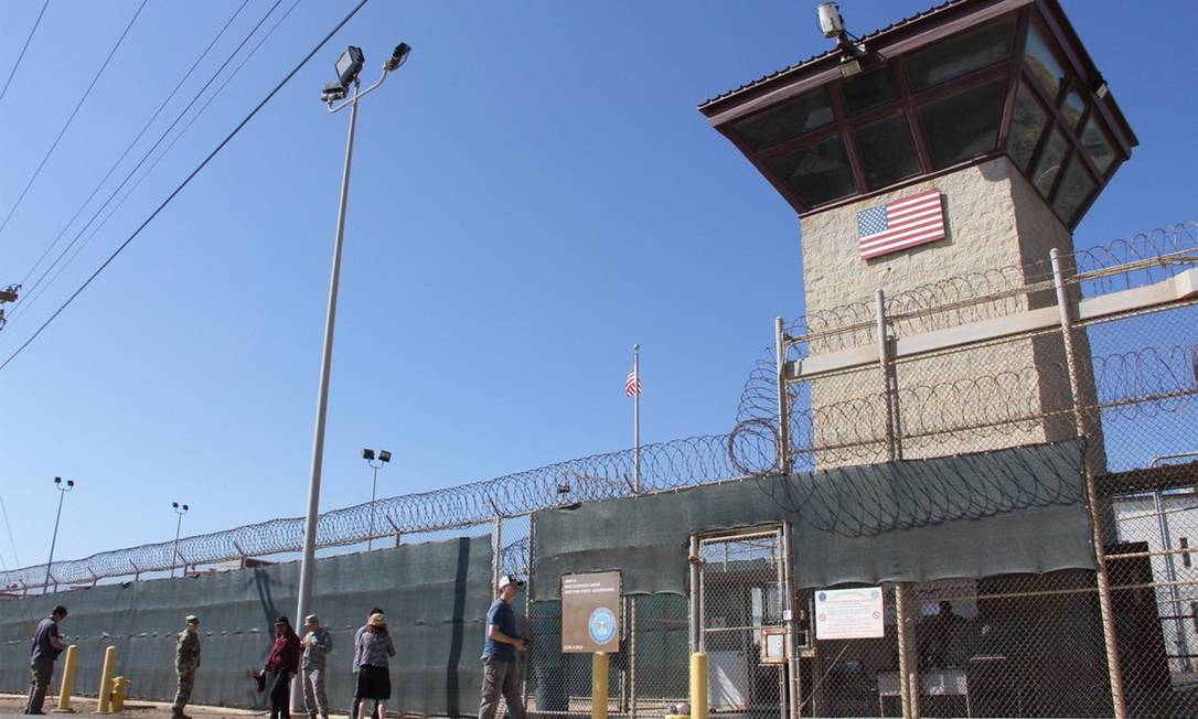 Pessoas caminham em frente a uma das torres da prisão americana de Guantánamo, em Cuba Foto: THOMAS WATKINS / AFP