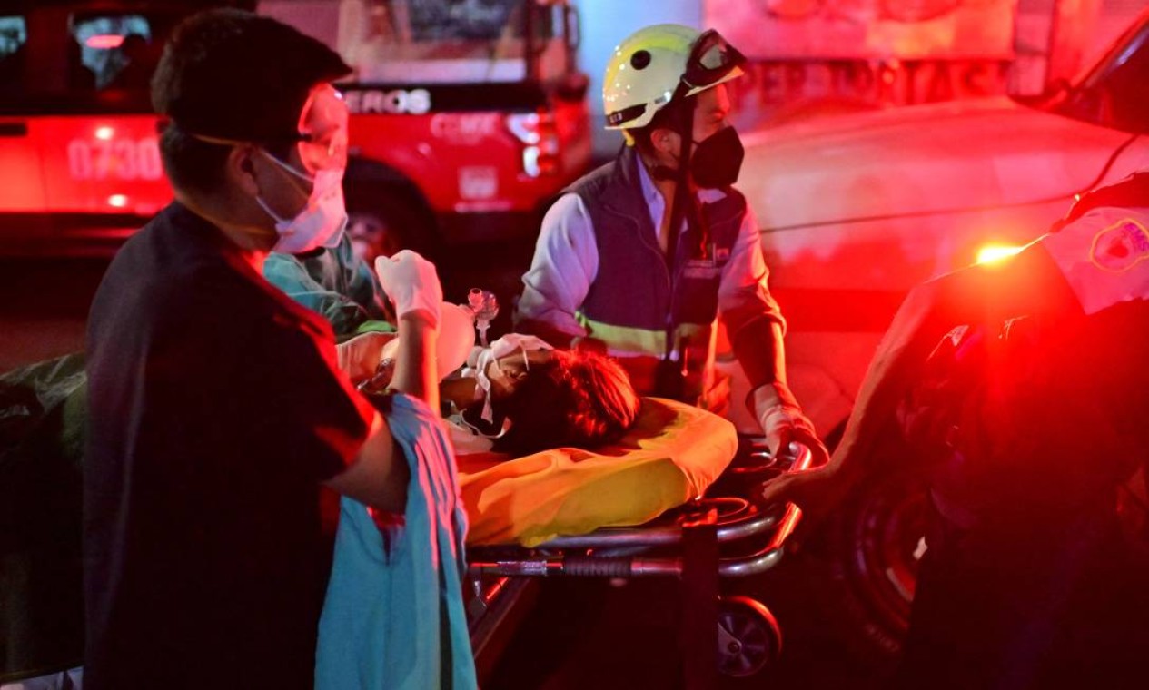 Trabalhadores de emergência movem uma pessoa ferida em uma maca no local do acidente Foto: PEDRO PARDO / AFP