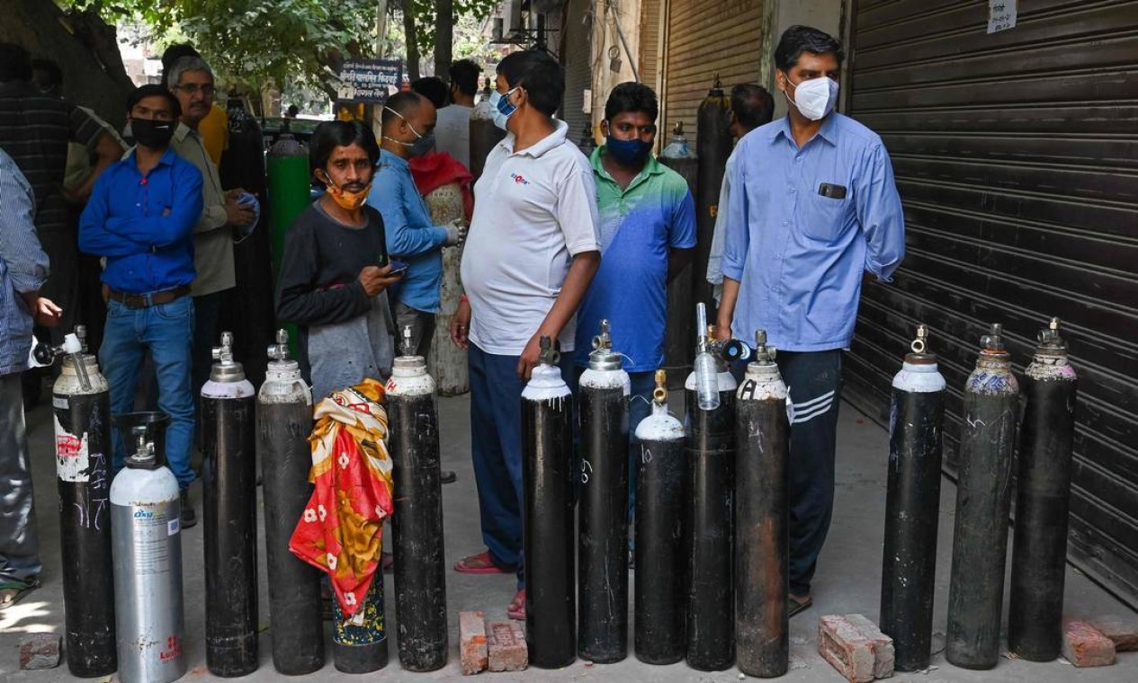 Familiares de pessoas com Covid-19 enfrentam longas filas para recarregar cilindro de oxigênio para tratamento domiciliar Foto: PRAKASH SINGH / AFP