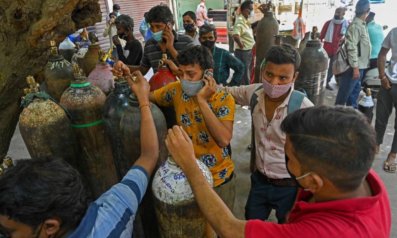 Indianos precisam pagar empresas privadas para recarregar cilindros de oxigênio para tratar familiares em casa Foto: PRAKASH SINGH / AFP