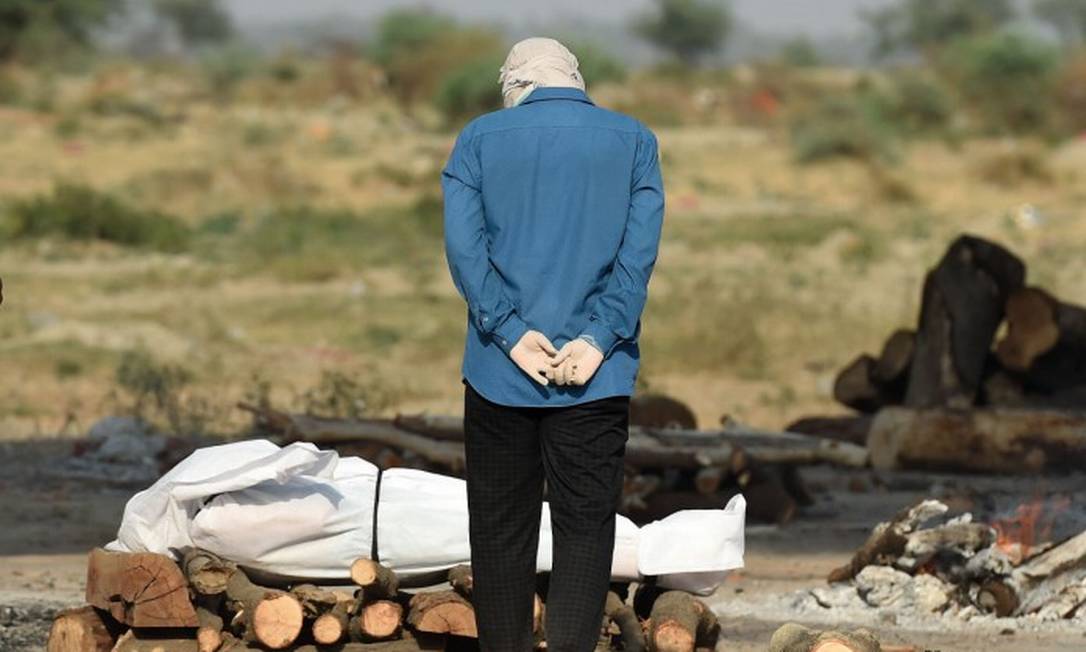 Homem observa corpo de parente morto pela Covid-19 enquanto aguarda cremação Foto: SANJAY KANOJIA / AFP