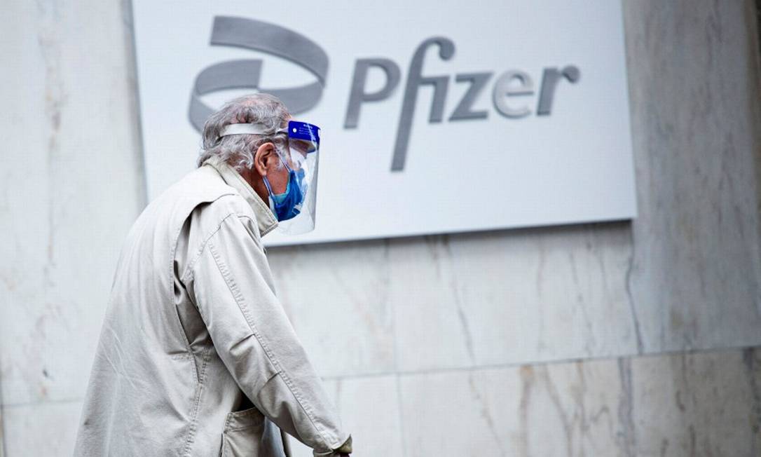 De máscara, homem caminha em frente à sede da Pfizer, em Nova York Foto: KENA BETANCUR / AFP/11-3-21