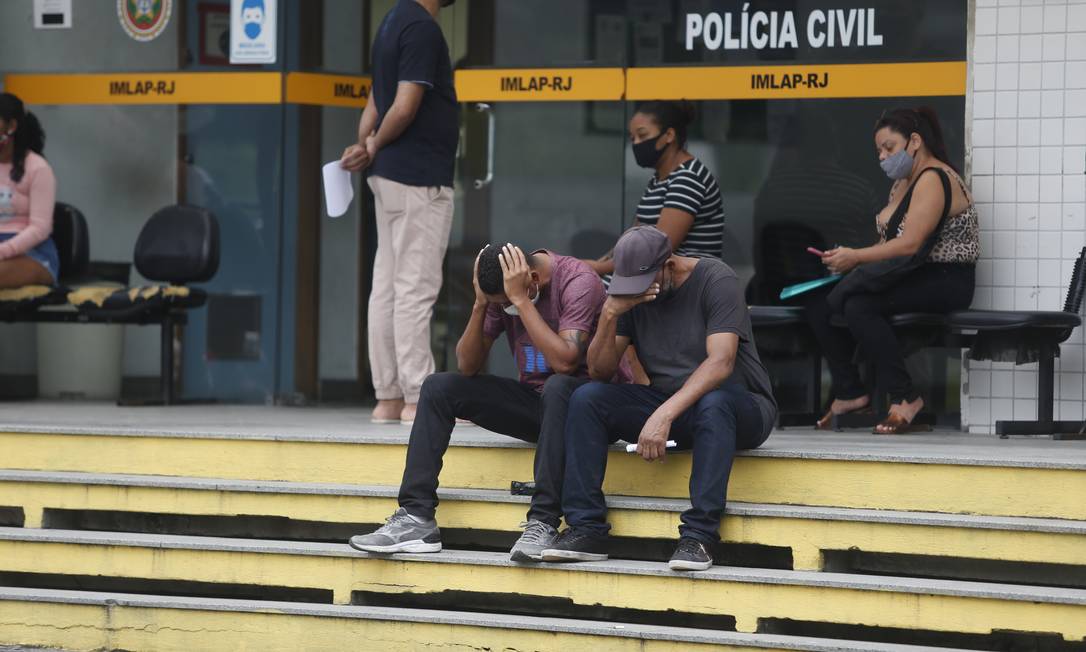 O irmão de uma das vítimas (sentado, de camisa roxa) foi até o IML Foto: Fabiano Rocha / Agência O Globo