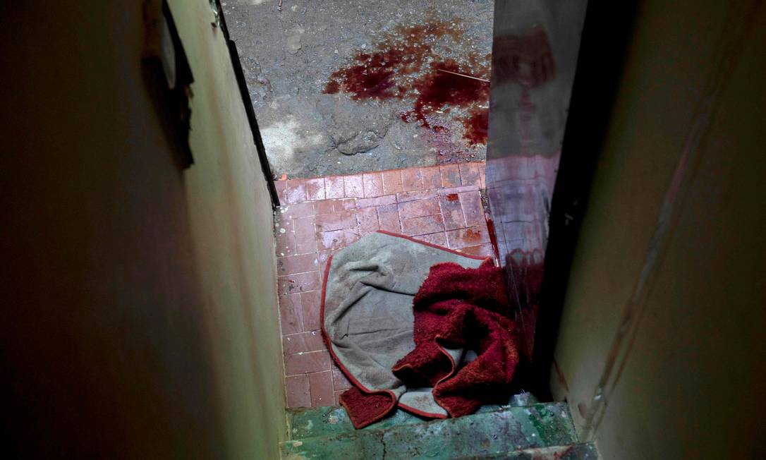 Roupa ensanguentada e poças de sangue são vistas à porta de casa no Jacarezinho Foto: Mauro Pimentel / AFP