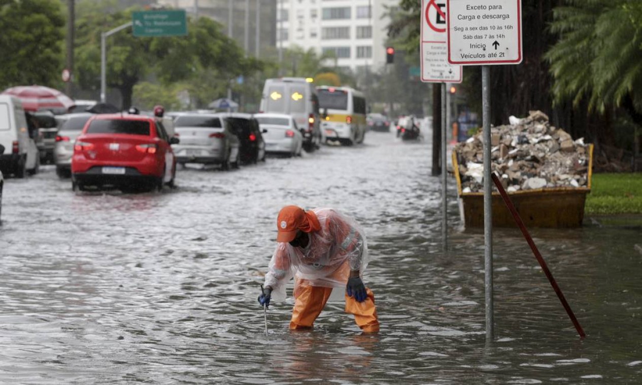 Servidor da Comlurb tenta abrir bueiro para escoar água da chuva Foto: Marcia Foletto / Agência O Globo