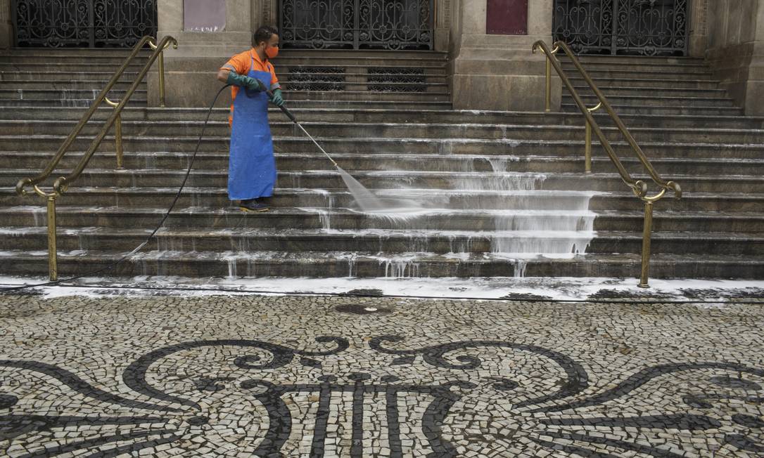 Funcionário da Comlurb higieniza as escadarias do Teatro Municipal com sabão, cloro e desinfetante Foto: Márcia Foletto