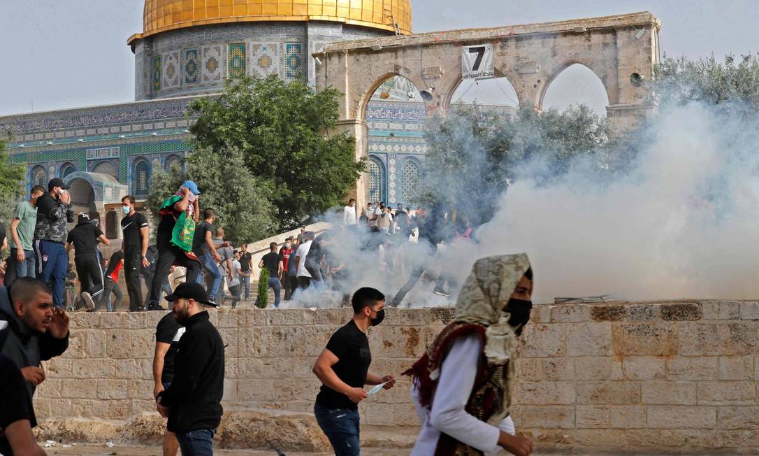 Palestinos correm para buscar proteção do gás lacrimogêneo lançado pelas forças de segurança israelenses durante o Dia de Jerusalém Foto: AHMAD GHARABLI / AFP
