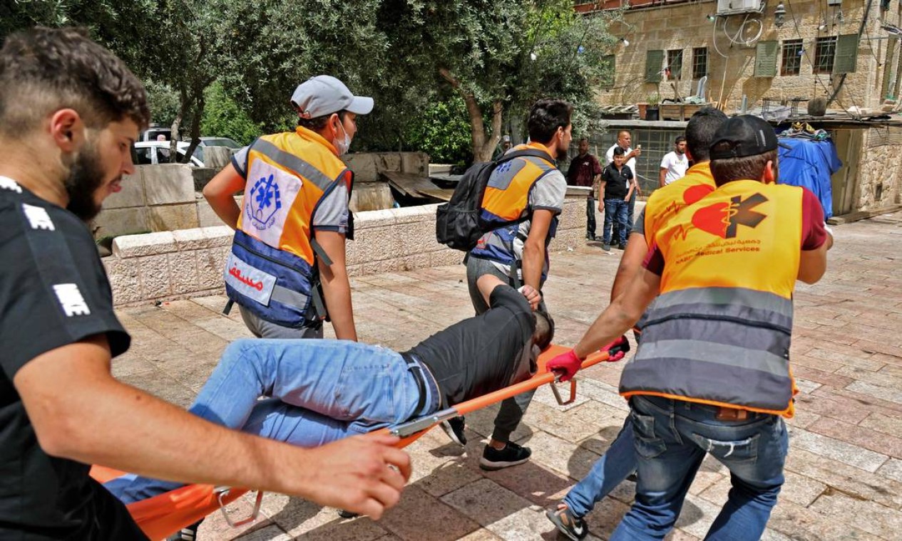 Médicos palestinos evacuam um manifestante ferido do complexo da mesquita de Aqsa, na Cidade Velha de Jerusalém Foto: AHMAD GHARABLI / AFP