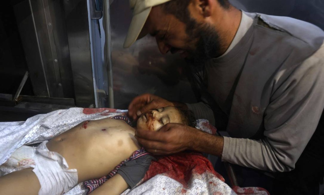 Homem palestino chora sobre o corpo de uma criança morta em meio a uma explosão de violência israelense-palestina, em um necrotério de hospital no norte da Faixa de Gaza Foto: MOHAMMED ABED / AFP