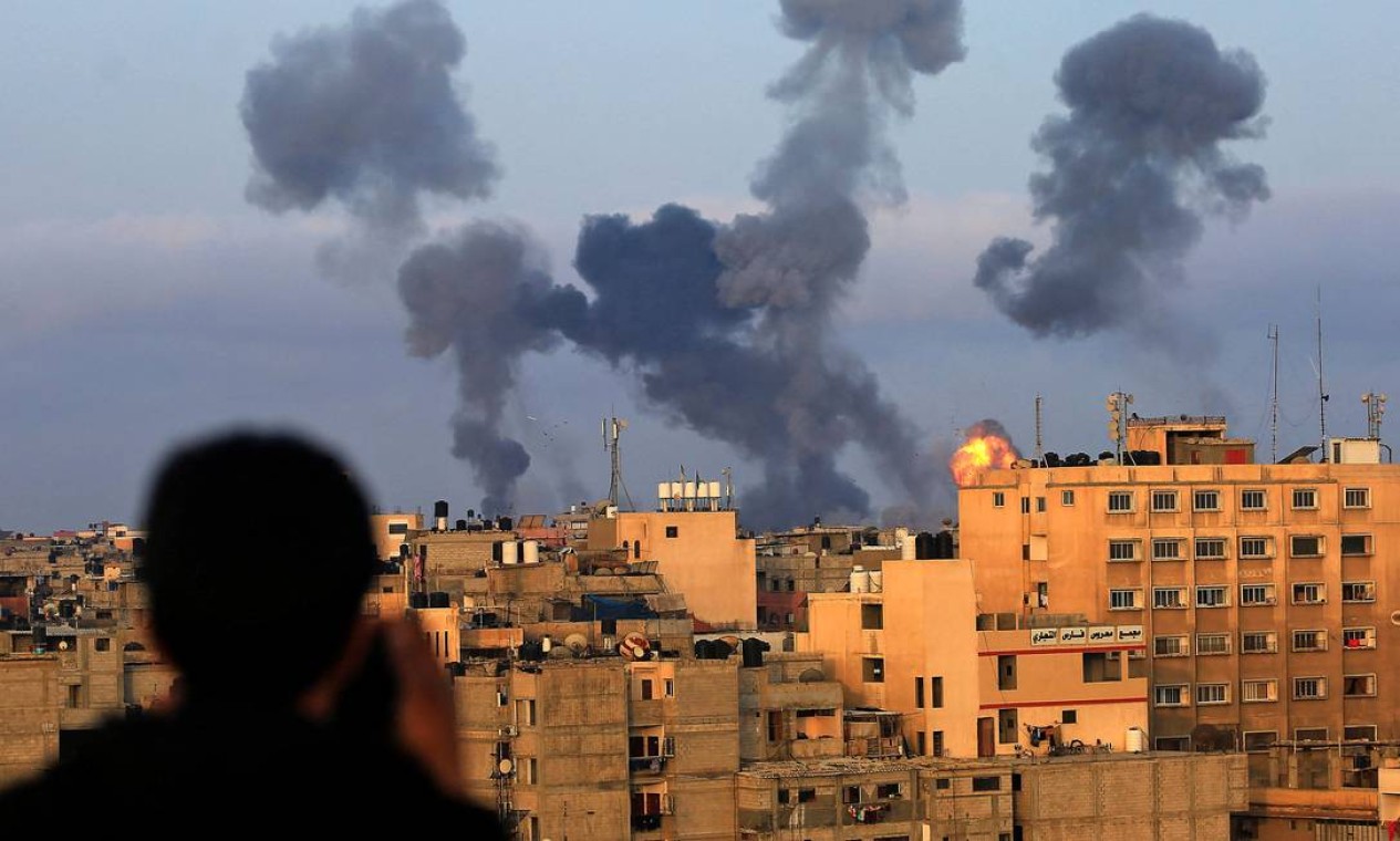 Menino palestino observa a fumaça saindo de alvos durante ataques aéreos israelenses na região de Khan Yunis, ao sul de Gaza, controlada pelo movimento Hamas Foto: MAHMOUD KHATAB / AFP