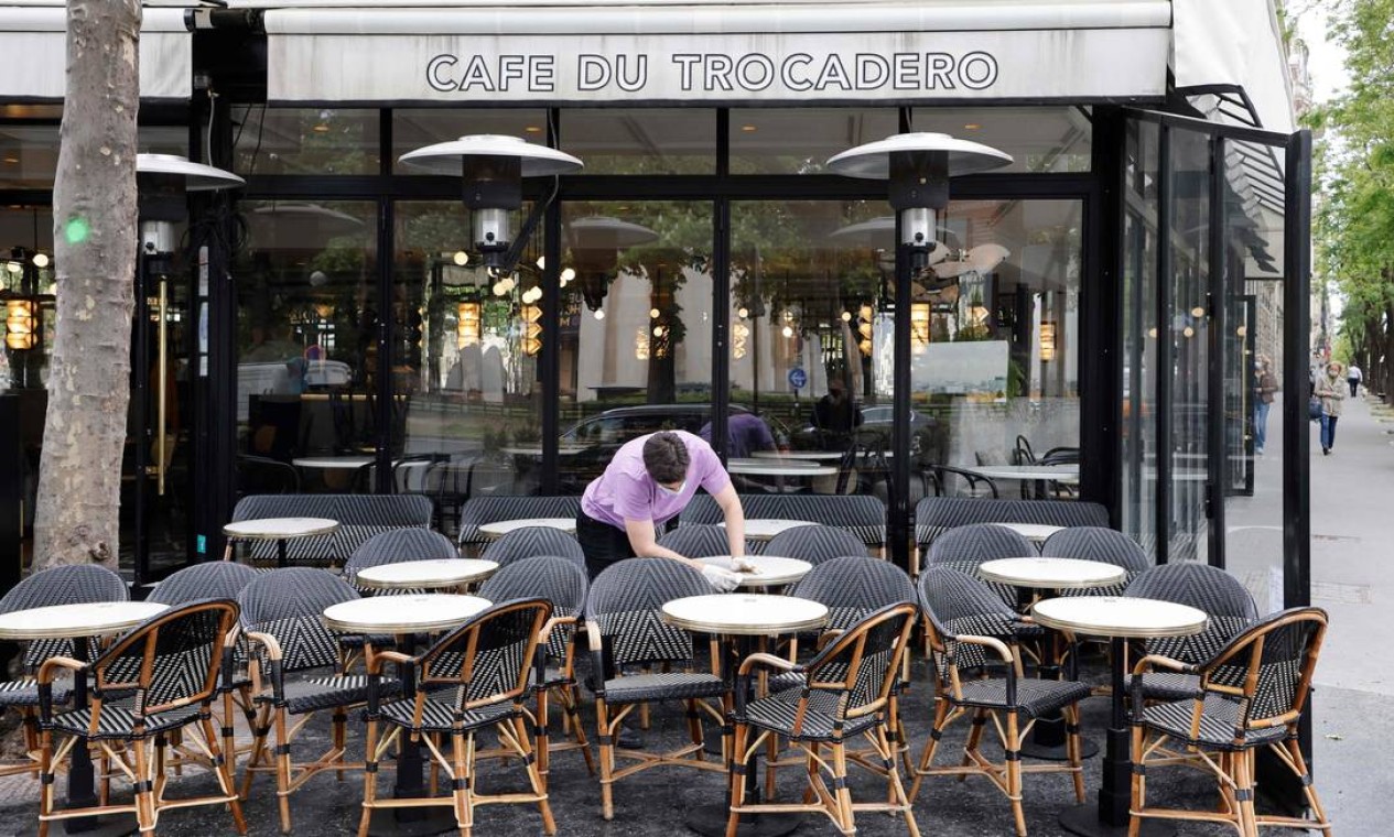 Funcionário limpa as mesas em um café em Paris, antes da reabertura dos restaurantes e cafés com mesas ao ar livre programada para 19 de maio Foto: LUDOVIC MARIN / AFP