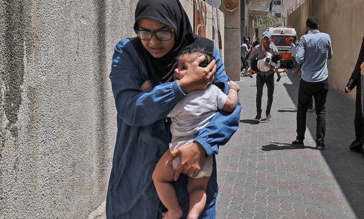 Palestina foge de prédio alvo do bombardeio israelense tentando proteger bebê Foto: MAHMUD HAMS / AFP