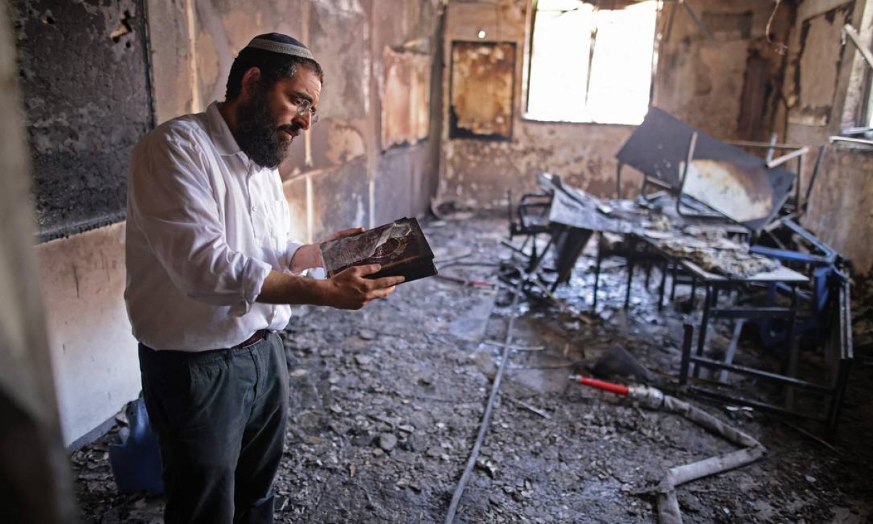 Um rabino inspeciona os danos dentro de uma escola religiosa incendiada na cidade israelense de Lod, perto de Tel Aviv Foto: AHMAD GHARABLI / AFP