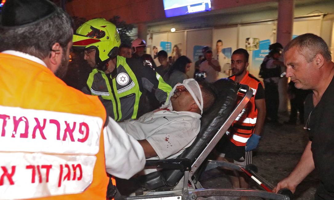 Serviços de emergência de Israel transpostam um homem ferido, em Holon, no distrito de Tel Aviv, após o grupo Hamas, que controla a Faixa de Gaza, disparar foguetes na cidade Foto: GIDEON MARKOWICZ / AFP