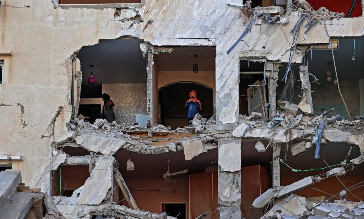 Mulheres palestinas verificam os danos dentro de um apartamento em um prédio fortemente danificado na Cidade de Gaza Foto: MOHAMMED ABED / AFP