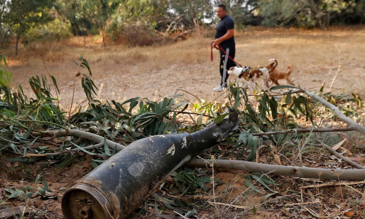 Um homem israelense passa pelos restos de um foguete disparado pelo grupo islâmico palestino Hamas da Faixa de Gaza e que foi destruído pelo sistema de defesa aérea de Israel, em Ashkelon Foto: JACK GUEZ / AFP