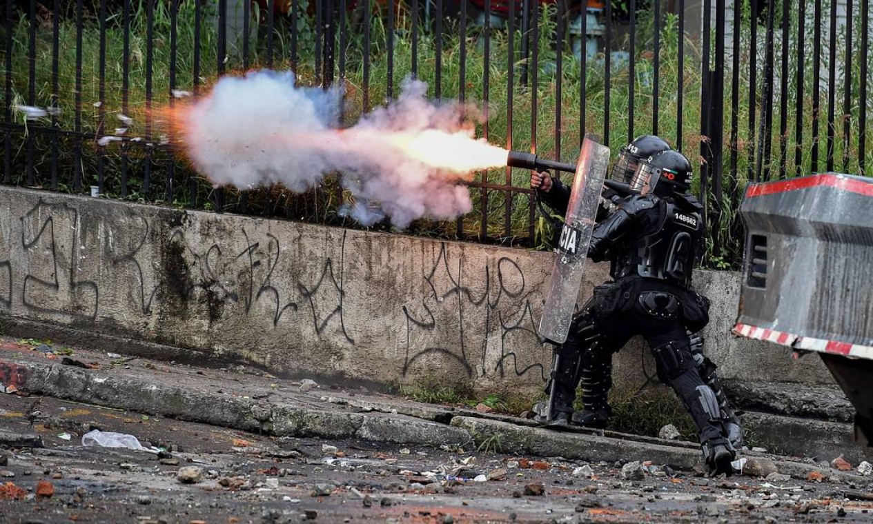 Um policial de choque dispara gás lacrimogêneo contra manifestantes durante um protesto contra o governo em Cali Foto: LUIS ROBAYO / AFP - 11/05/2021