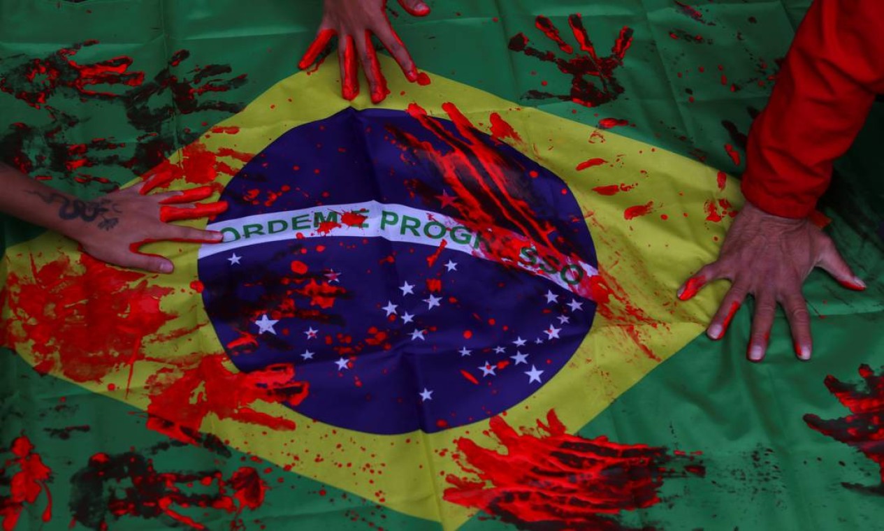 Ativistas tingem bandeira do Brasil usando as mãos pintadas com tinta vermelha em protesto contra a ação policial, considarada a mais letal da história do Rio, realizada na favela do Jacarezinho Foto: AMANDA PEROBELLI / REUTERS