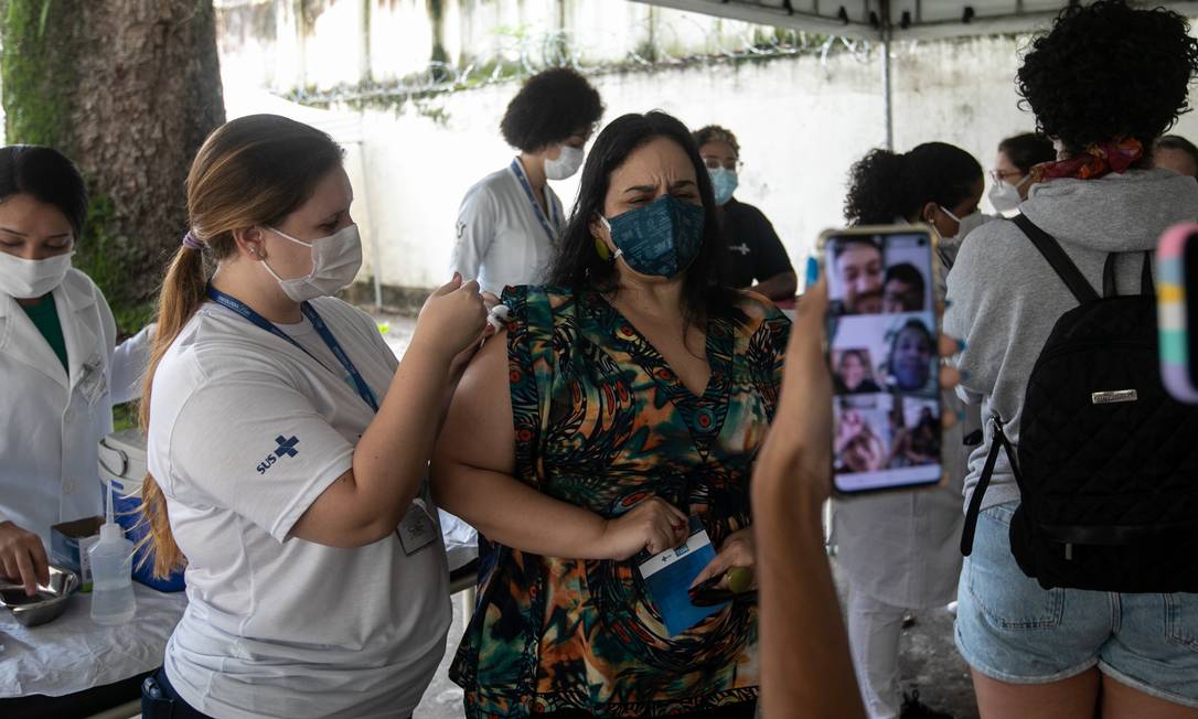Mulher que foi se vacinar levou amigos e familiares por teleconferência para participar da procedimento Foto: Brenno Carvalho / Agência O Globo
