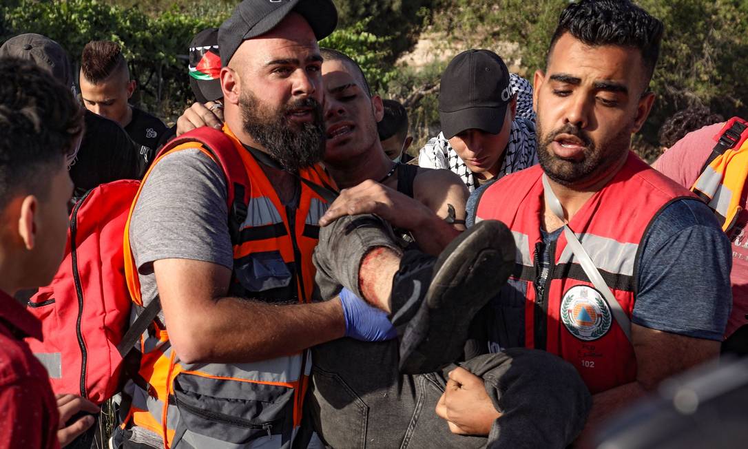 Equipes de resgate retiram um palestino ferido após confrontos com as forças de segurança israelenses durante um protesto perto do assentamento de Beit El, na Cisjordânia Foto: ABBAS MOMANI / AFP