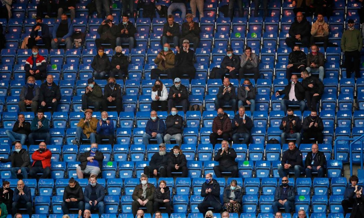 Torcedores assistem ao jogo durante a partida de futebol da Premier League inglesa entre Chelsea e Leicester City em Stamford Bridge, Londres, com esquema especial de ocupação das arquibancadas Foto: PETER CZIBORRA / AFP