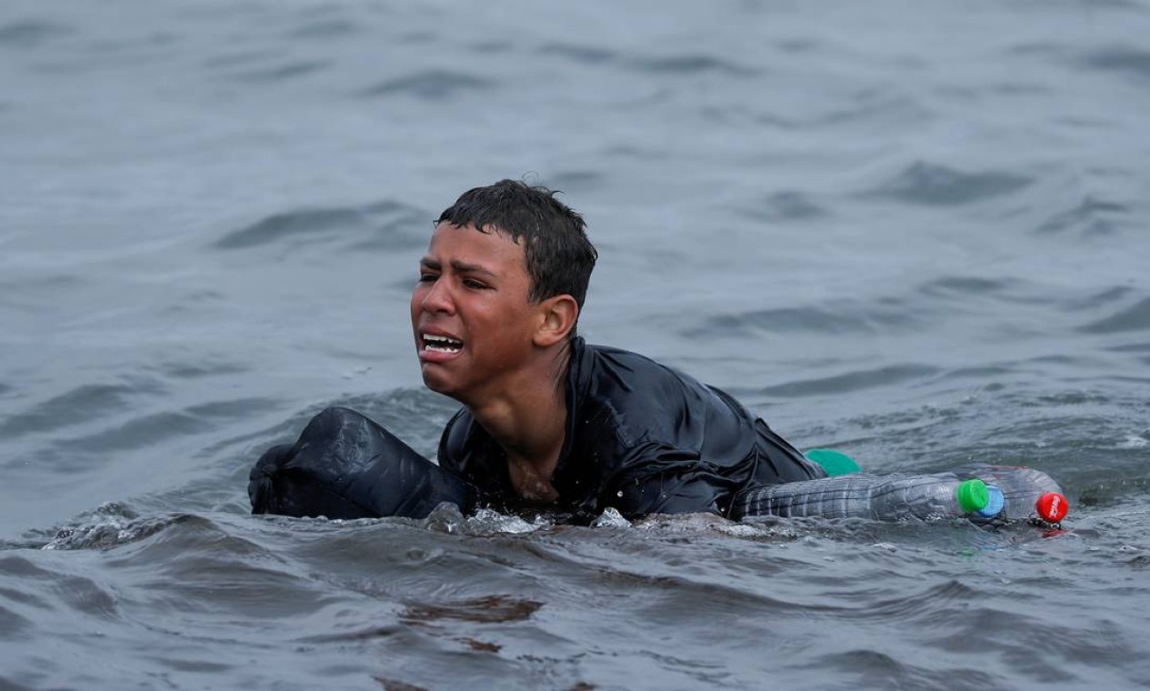Menino marroquino chora nadando usando garrafas como flutuadores, próximo à cerca entre a fronteira hispano-marroquina, em Ceuta, Espanha Foto: JON NAZCA / REUTERS