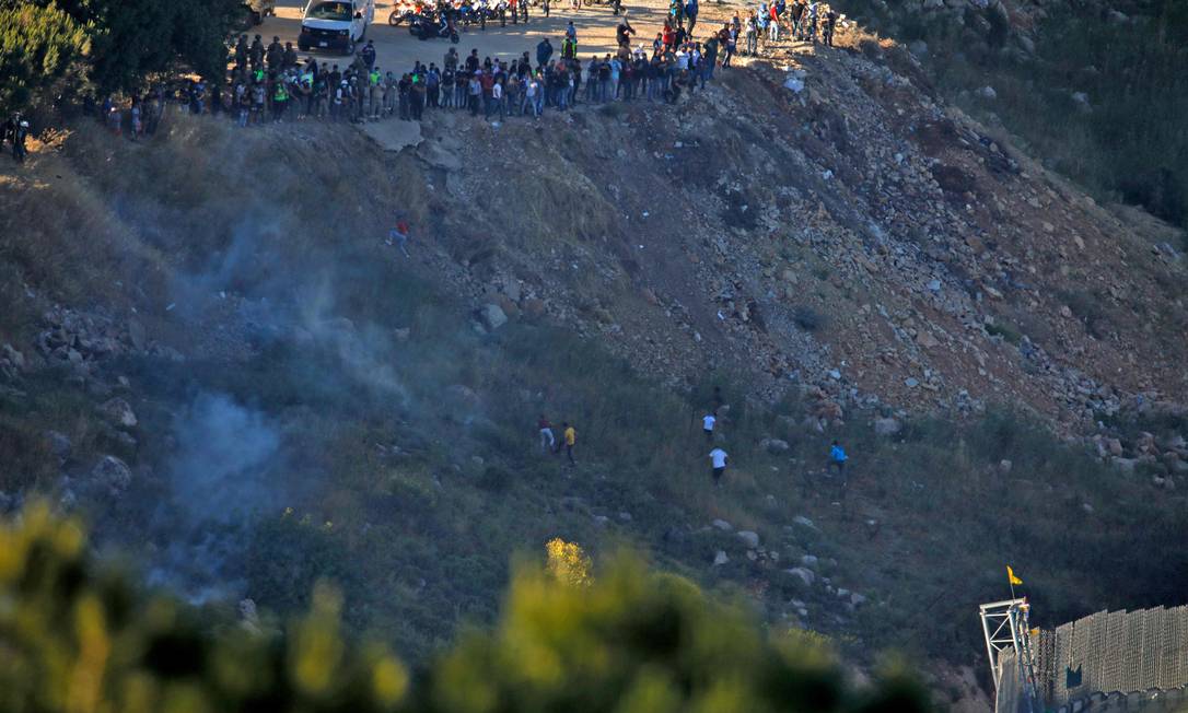 Palestinos no Líbano fogem das bombas de gás de tropas israelenses lançadas depois que manifestantes colocaram bandeira do Hezbollah na cerca que divide os dois países Foto: JALAA MAREY / AFP