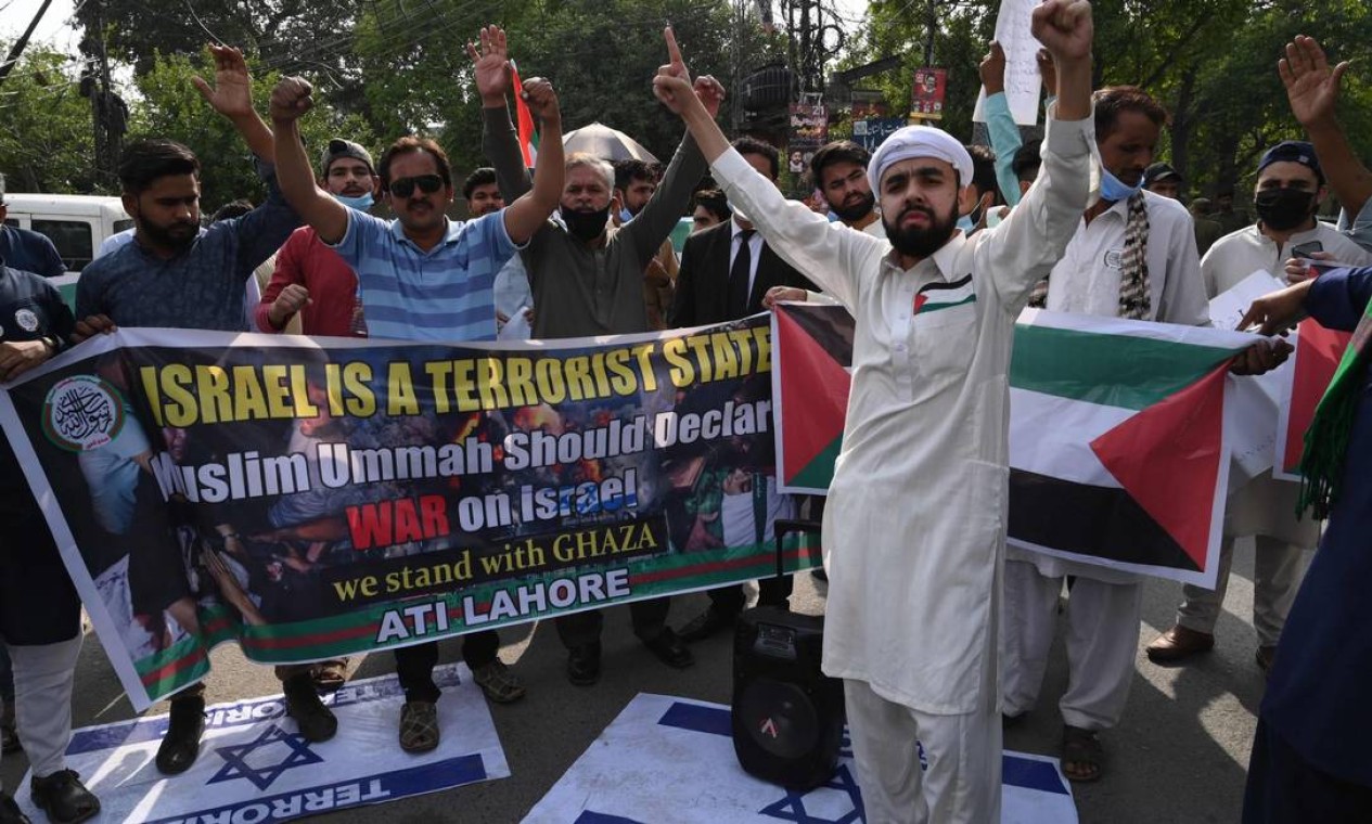 Manifestantes se posicionam sobre as bandeiras israelenses com as palavras "terrorista" durante uma manifestação em apoio à Palestina, em Lahore, em 18 de maio de 2021. (Foto: Arif ALI / AFP) Foto: ARIF ALI / AFP - 18/05/2021