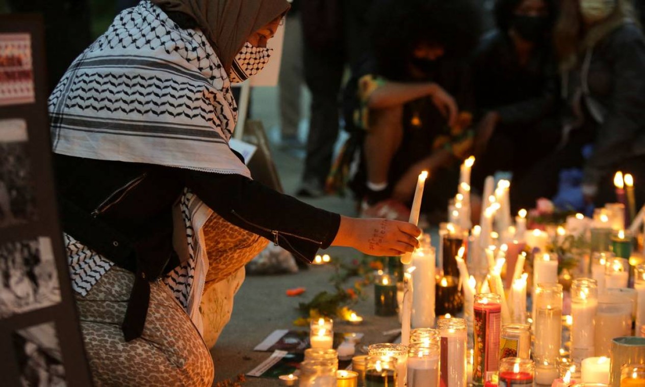 Tehreem Sabir, de Seattle, EUA, tem "Palestina Livre" escrita em sua mão enquanto acende uma vela durante uma vigília em solidariedade aos palestinos Foto: JASON REDMOND / AFP - 18/05/2021
