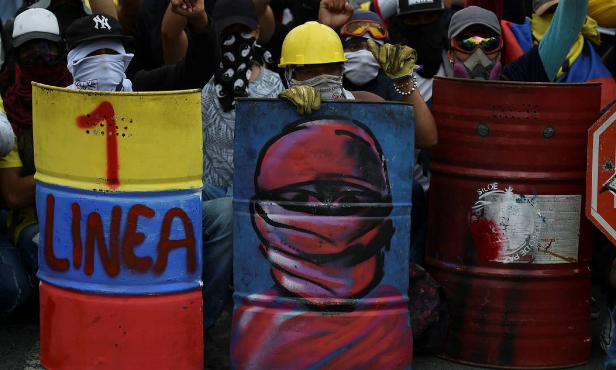 Manifestantes seguram escudo caseiro improvisados com barris de latão em protesto contra o governo do presidente colombiano Ivan Duque, em Cali Foto: LUIS ROBAYO / AFP